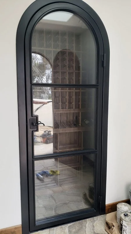 Modern arched iron door with a single clear glass panel