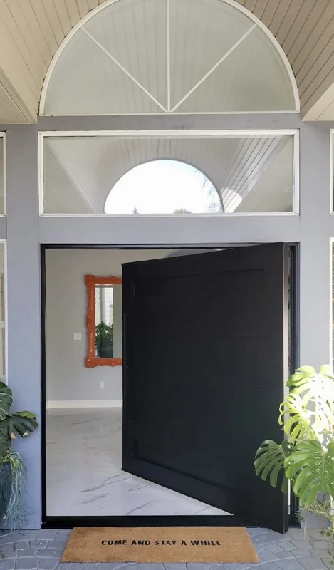 Oversized black pivot entry door in a light filled foyer
