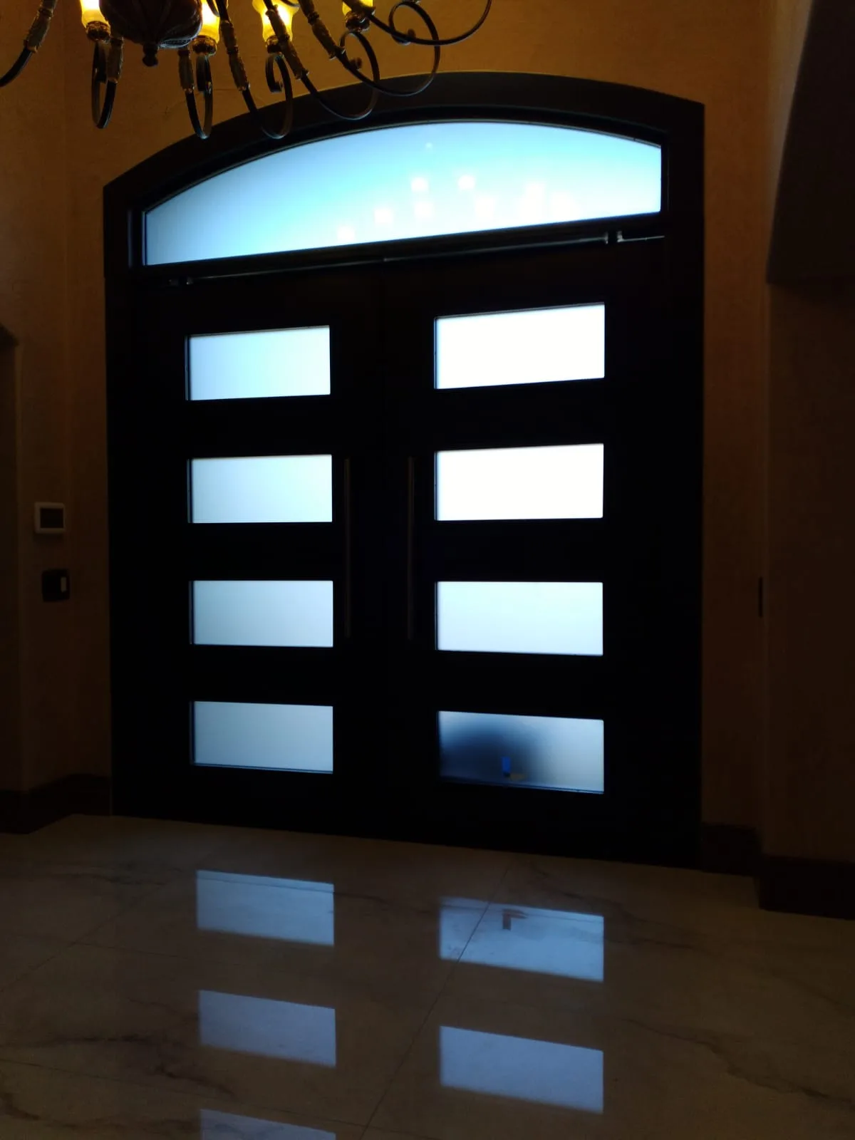 Modern black double entry doors with frosted glass panels and arched transom